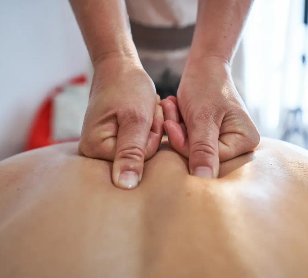 fisioterapeuta dando un masaje deportivo en la espalda a un paciente